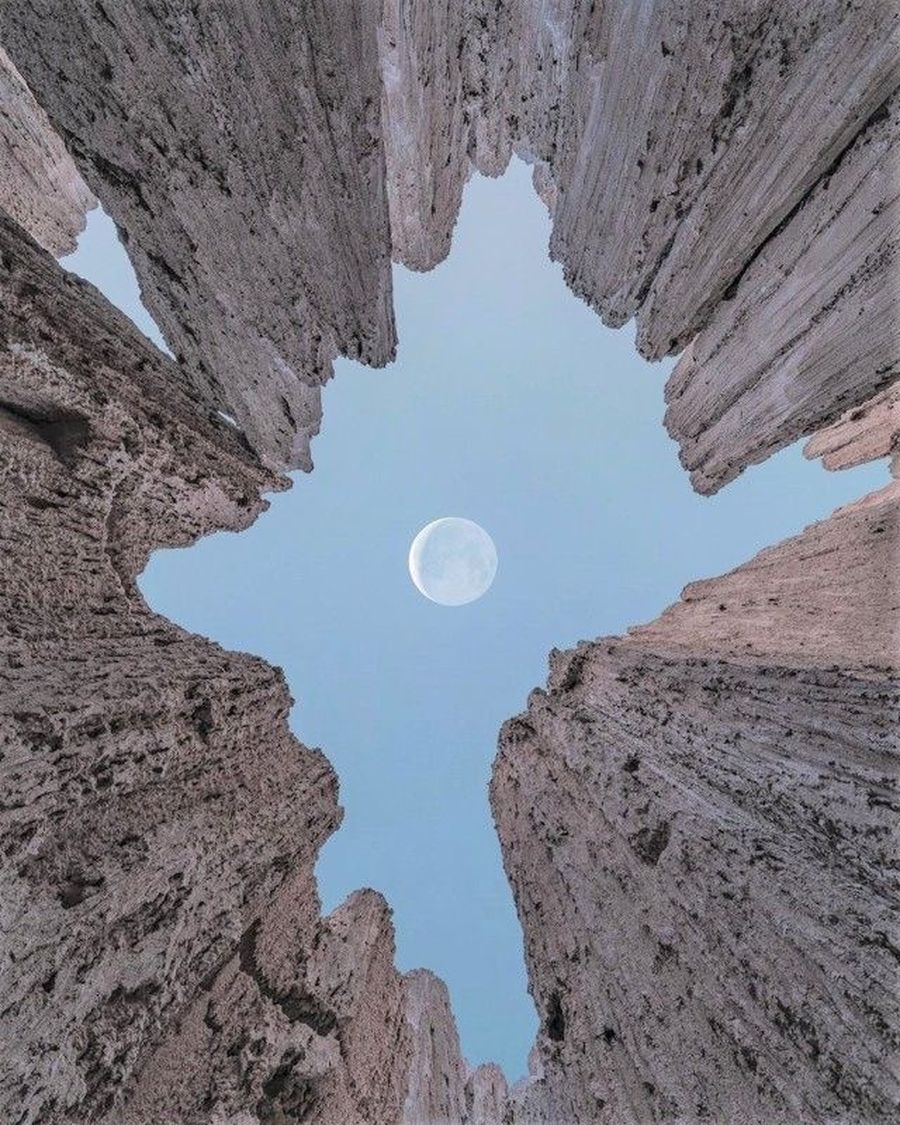 Un cañón visto desde abajo, abierto al cielo con la luna